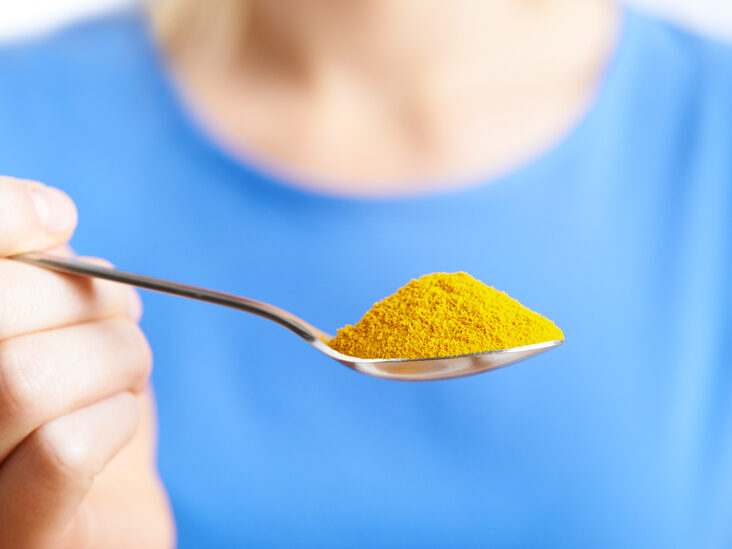 close-up-of-woman-with-spoonful-of-tumeric-powder