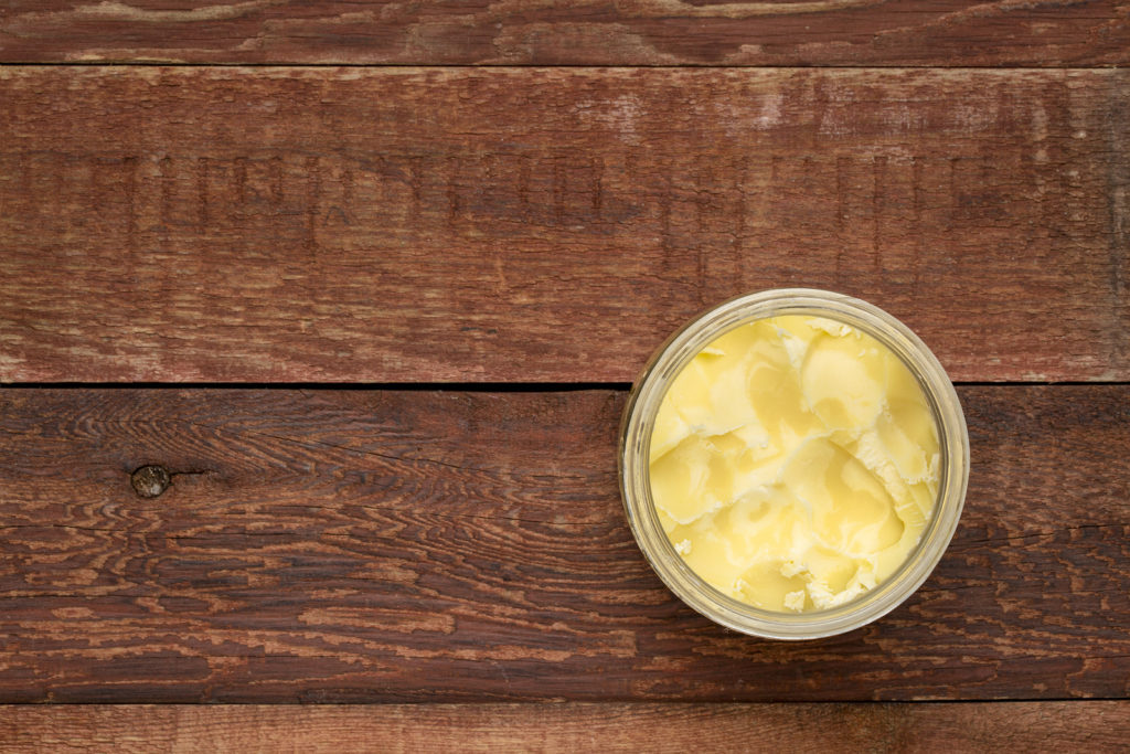 open-glass-jar-of-ghee-clarified-butter-on-a-rustic-barn-wood