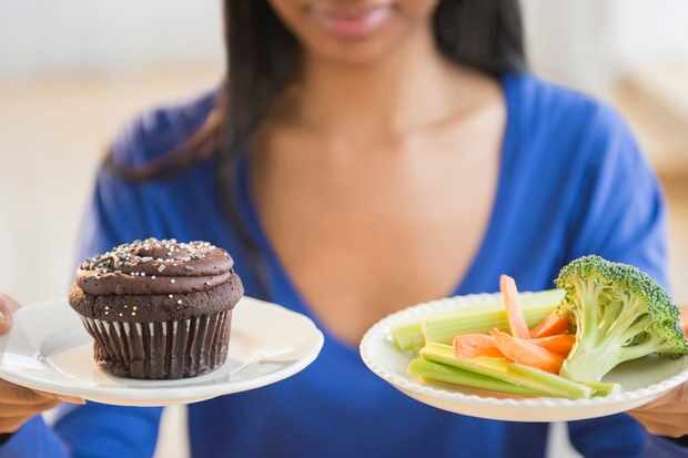 mixed-race-woman-choosing-vegetables-or-cupcake