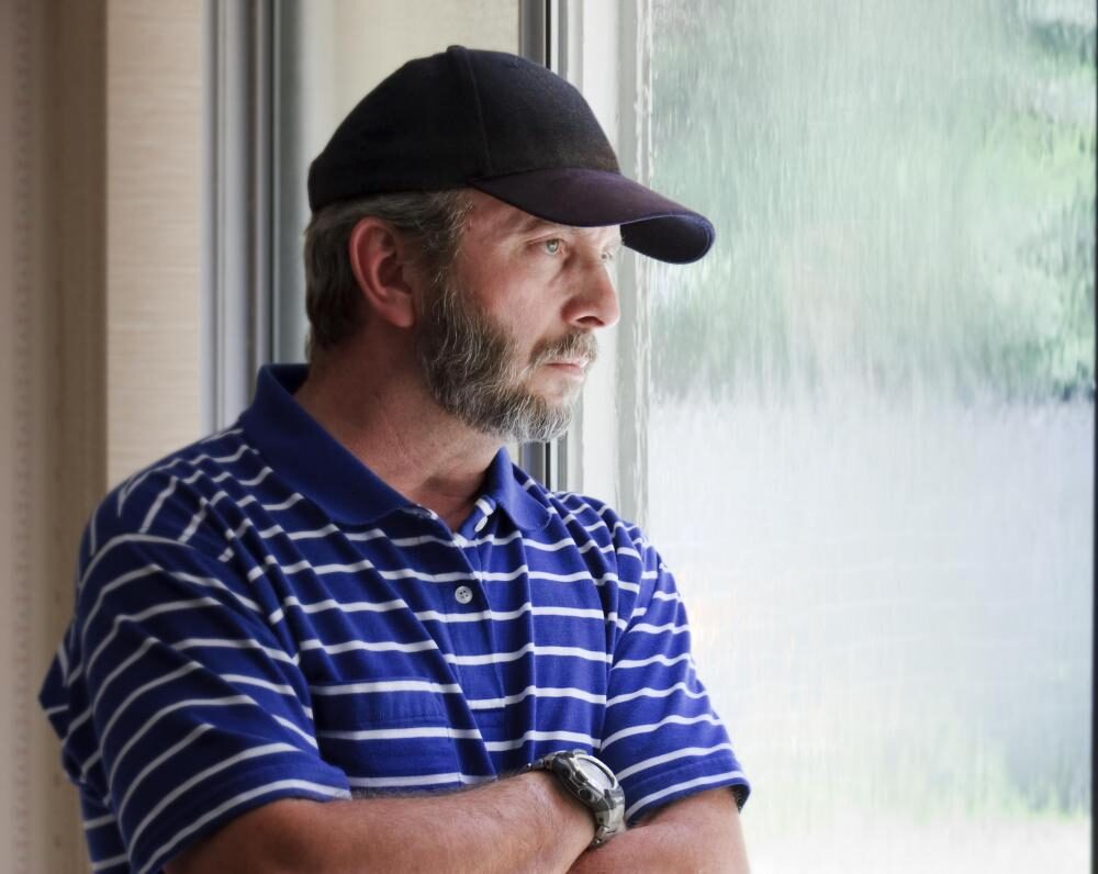 man-in-blue-striped-shirt-looking-out-window-at-rain-7563209